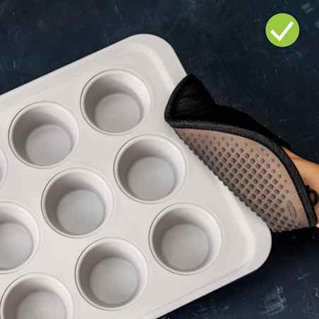 Person wearing a black pot holder to grab the edges of a spacious grey muffin tin